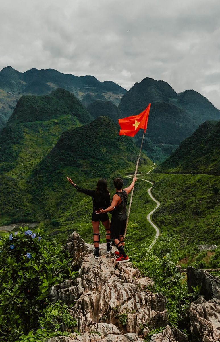 Couple holding a flag on a mountain ridge