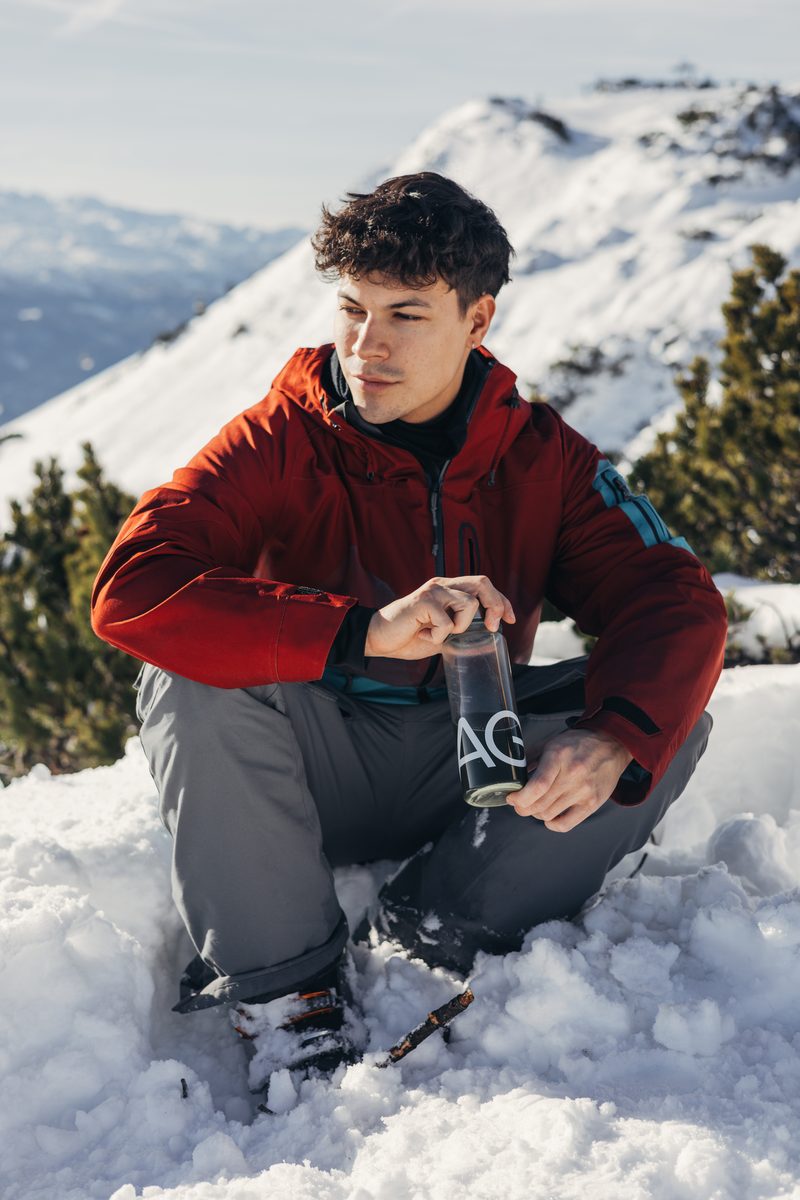 Man on a snowy mountain holding a bottle